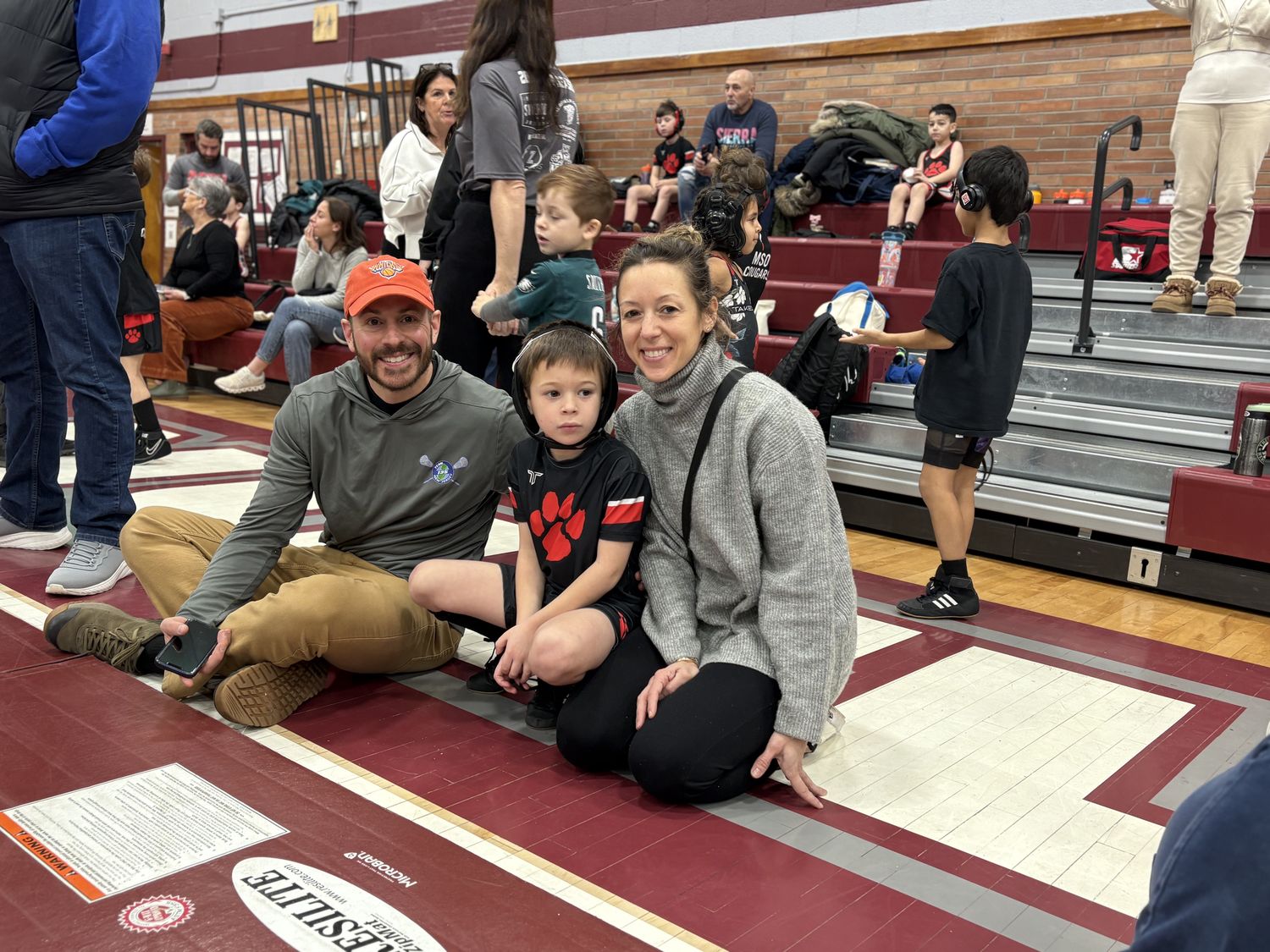 An MSO wrestler sitting matside with his parents at a tournament.