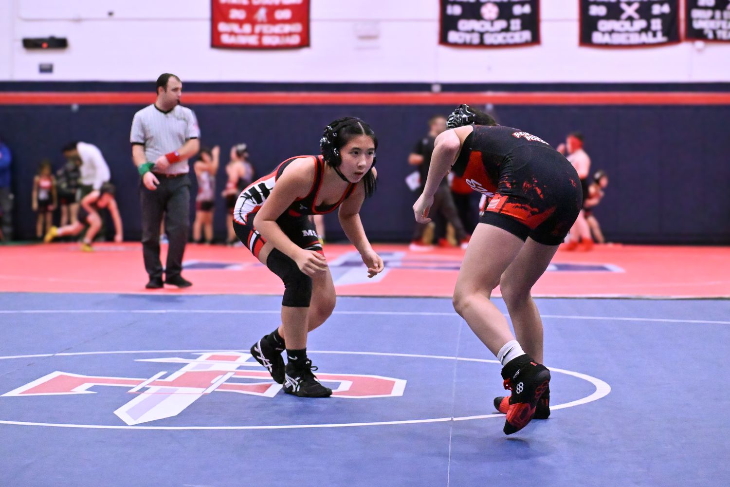 An MSO girl wrestler in stance, facing her opponent at the center of the mat.