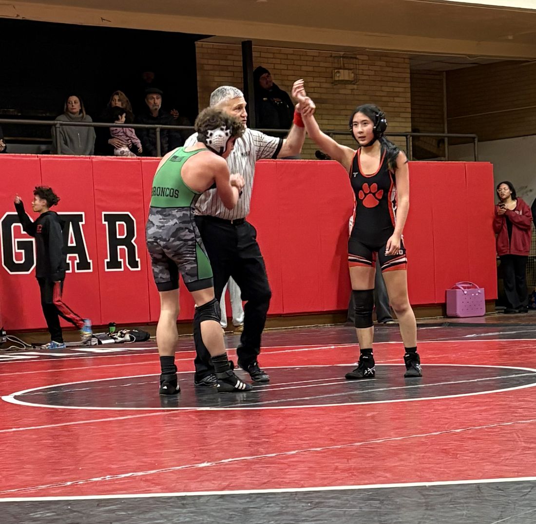 A referee raising an MSO girl wrestler's hand after her match.