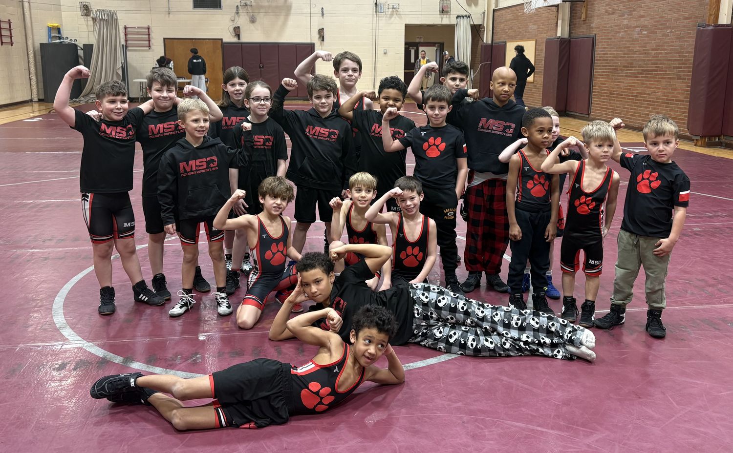 MSO's youngest wrestlers flexing for a team photo on the mat.